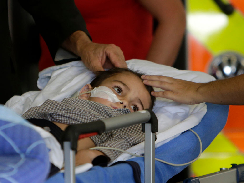 A 5-year-old boy with a brain tumor lies down on a stretcher when he arrives with his parents.  Reuters